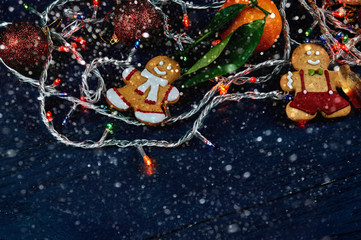 Obraz na płótnie Canvas Lovely Christmas decoration close-up. New Year's things and sweets on a black wooden table. The gingerbread man keeps a cola of chewing marmalade.