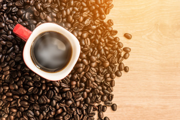 Coffee cup and coffee beans with smoke on wooden