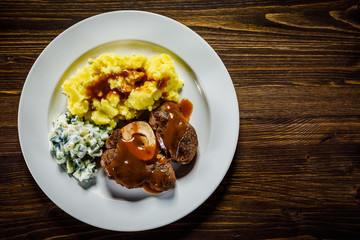 Grilled steak boiled potatoes and vegetable salad on wooden background