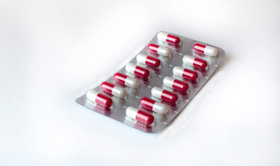 Blister with white and red capsules, isolated on white background. Close-up medical drugs