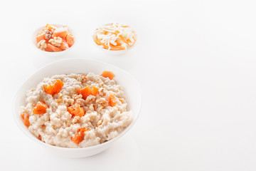 Fototapeta na wymiar Oatmeal with pumpkin and nuts in a plate and vegetable salads on a white background. Close-up. Copy space