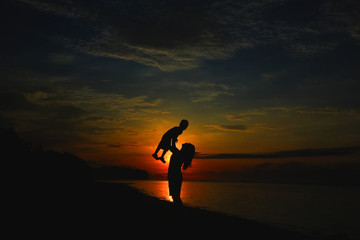 mother and daughter silhouette playing on the beach
