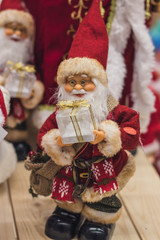 Santa Claus as Toy in red suit costume in a cap and gold-rimmed glasses with a blush on the cheeks carry gifts sale, market, realization in the shop