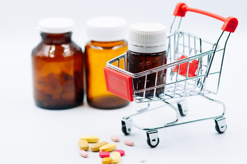 Small shopping cart full of bottle on white background. Medicine and pharmacy concept