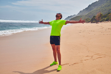 Man celebrating success after good training / exercise on a sandy ocean beach.