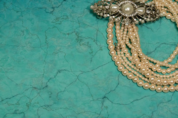 Pearl necklace and hair accessaries on green background