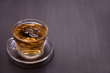 Cup of chinese green tea on a wooden background. Flower -tea blooming in a cup.