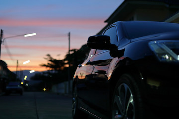 luxury vehicle black car with blur twilight dramatic sky, image selective focus on side mirror
