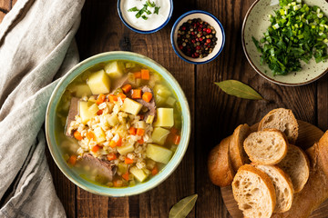 Rassolnik - Traditional Russian soup with pickled cucmbers, pearl barley, meat, pickles, carrots and potatoes on a dark wooden background. Top view