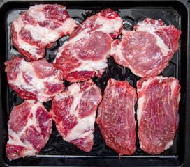 Pieces of pork chops on an iron tray 