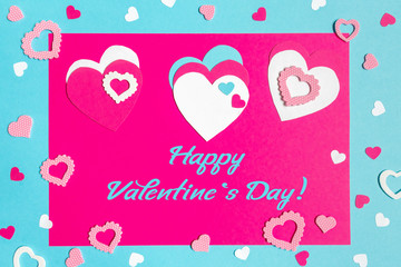 Valentine s Day greeting card. 14th of february. Happy Valentines Day Lettering with cut paper hearts on blue pink background with text happy valentines day