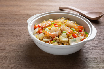 close up of fried rice with shrimp in a ceramic bowl on wooden table. homemade style food concept.