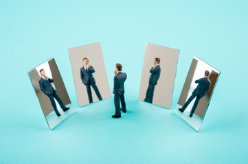 A miniature suited man surrounded by four mirrors 