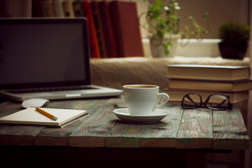 A cup of coffee in the workplace on a wooden table.