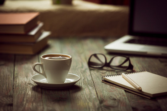 A cup of coffee in the workplace on a wooden table.