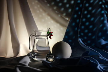 Still life transparent glass jar with water sprig of berries large white frosted ball and small glossy ball on a white-blue background with light shadows