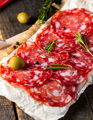 Chorizo sausage and salami, thin cut. spanish salami on the wood background with spices, paprika, pepper. Spicy food. Chili.