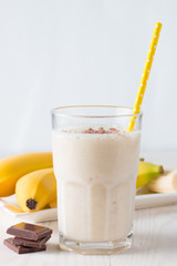Fresh Made Chocolate Banana Smoothie on a wooden table. Selective focus. Milkshake with almonds. Protein diet. Healthy food and drink concept.