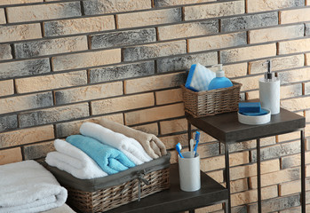 Obraz na płótnie Canvas Tables with soap, towels and other toiletries near brick wall