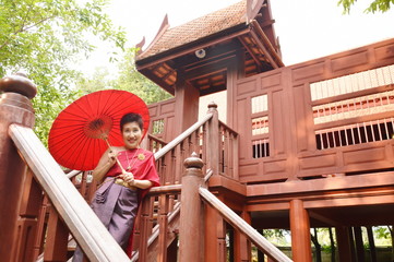 Asian elder woman dressing retro Thai costume in wooden ancient house