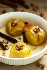 Baked apples with raisins, hazelnuts and cinnamon on wooden background. Rustic style.