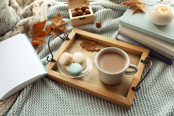Tray with breakfast near stack of books on knitted plaid