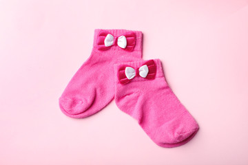 Pair of cute child socks on color background, top view
