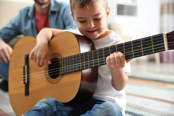 Father watching his son playing guitar at home