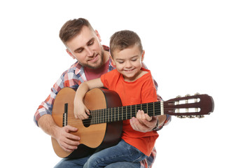 Father teaching his little son to play guitar on white background