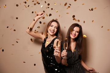Beautiful women with glasses of champagne and confetti on color background © New Africa
