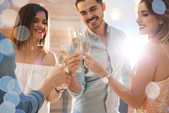 Friends clinking glasses with champagne at party indoors