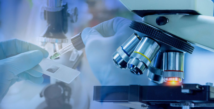  Close up shot of microscope equipment with metal lens in laboratory. Researcher hands in rubber gloves using a dropper and microscope to study a sample for developing a new drug and new substance.