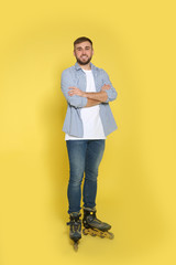 Full length portrait of young man with inline roller skates on color background