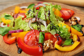 Fresh vegetable salad with balsamic vinegar on wooden plate, closeup