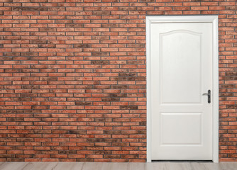 White wooden door in brick wall. Space for text