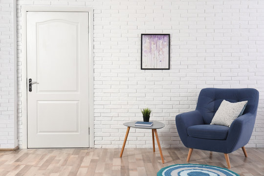 Light room interior with white door in brick wall