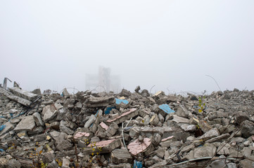 The remains of concrete fragments of gray stones on the background of the destroyed building in a foggy haze. Copy space