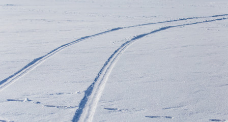 Obraz premium Traces of cars on white snow as a background