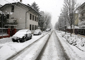 snowy road during a snowfall in the city with some cars