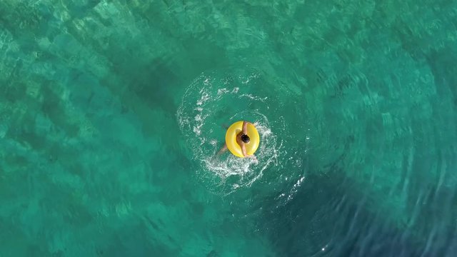 Aerial view of woman spinning with inflatable on Atokos island, Greece.