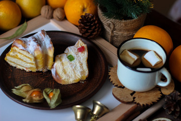 View of Christmas decor. Christmas objects: dried sliced orange, cinnamon, pine cone, fir branch, cup coffee, cheesecake, walnut, golden Christmas bells.