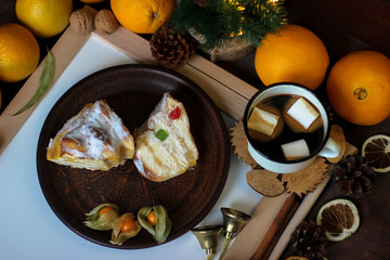 View of Christmas decor. Christmas objects: dried sliced orange, cinnamon, pine cone, fir branch, cup coffee, cheesecake, walnut, golden Christmas bells.