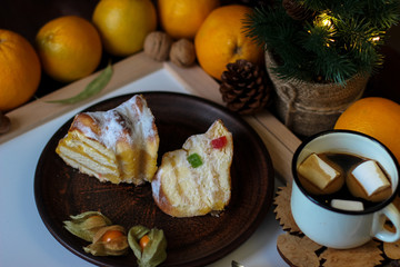 View of Christmas decor. Christmas objects: dried sliced orange, cinnamon, pine cone, fir branch, cup coffee, cheesecake, walnut, golden Christmas bells.