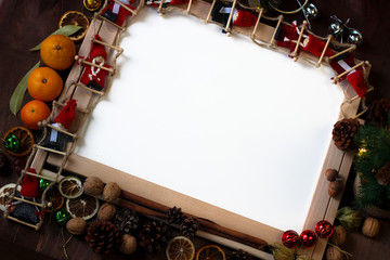 Top view of Christmas decor with copy space area. Christmas objects: dried sliced orange, mandarines, cinnamon, pine cone, fir branch, cup coffee, cheesecake, walnut, golden Christmas bells