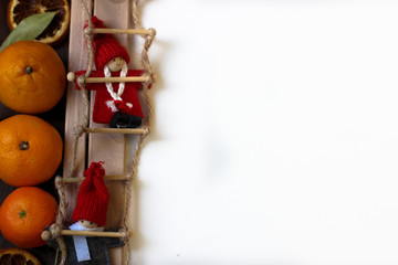 Top view of Christmas decor with copy space area. Christmas objects: dried sliced orange, mandarines, cinnamon, pine cone, fir branch, cup coffee, cheesecake, walnut, golden Christmas bells