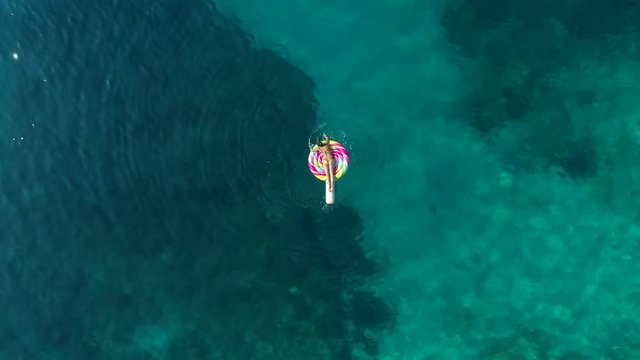 Aerial view of woman floating on inflatable lollipop on Atokos island, Greece.