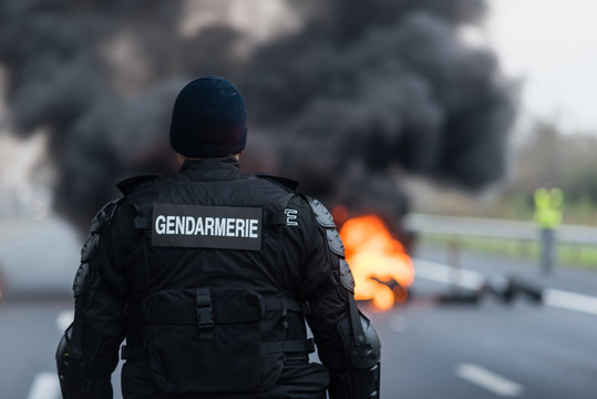 gendarme face &agrave; un feu de pneus lors d'une manifestation - blocage routier