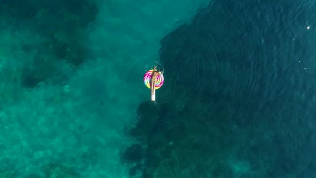 Aerial view of woman floating on inflatable lollipop on Atokos island, Greece.