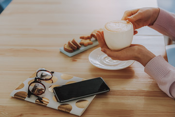 Close up of a coffee cup on hands of a woman