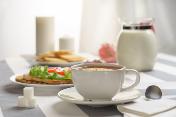 Fresh, tasty breakfast with a sandwich and tea on a light background.